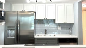 A modern kitchen with stainless steel appliances, white cabinets, and a tiled backsplash. - FABULOUS WATERFRONT STUDIO APT IN ST PETE FL! (Saint Petersburg)