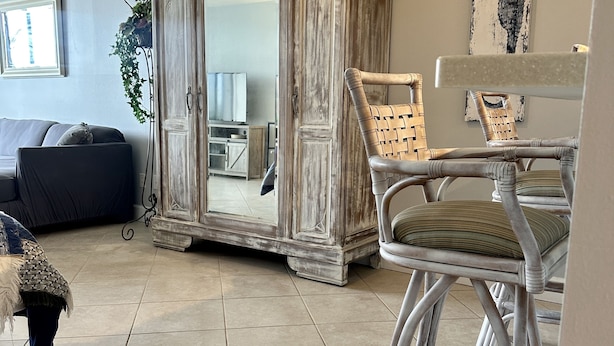 A living room with a large mirror, wicker chairs, a sofa, and a ceiling fan. - FABULOUS WATERFRONT STUDIO APT IN ST PETE FL! (Saint Petersburg)