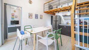 A modern kitchen with a dining area, featuring a white table, green chairs, and a stainless steel refrigerator. - Yeosu Sea&blue Family Pension (Yeosu)