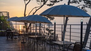 Outdoor seating with umbrellas, a view of the sea, and a railing. - Yeosu Sea&blue Family Pension (Yeosu)