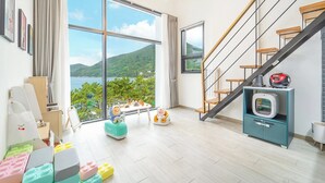 Ein Zimmer mit einem großen Fenster, einer Treppe und Blick auf eine gebirgige Landschaft.