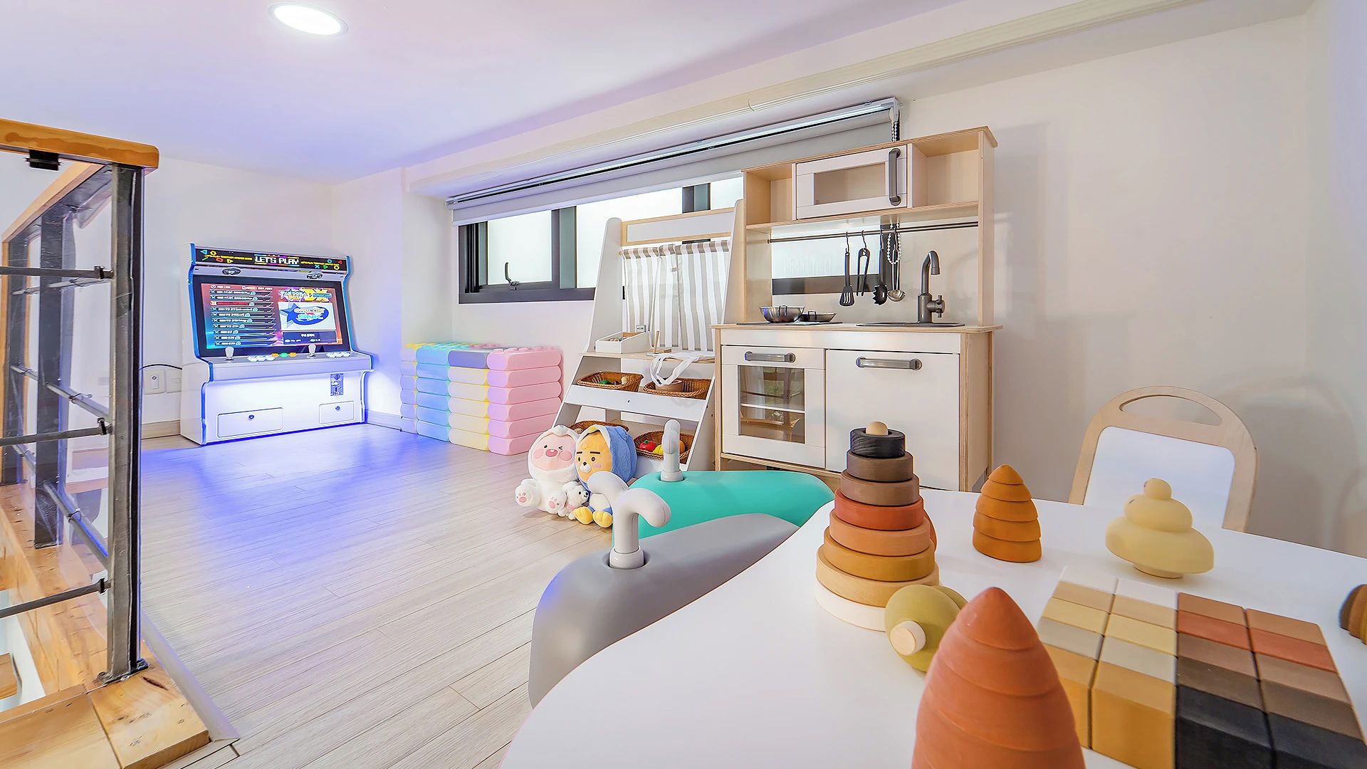 A child's play area with a gaming console, toys, and a kitchen setup.