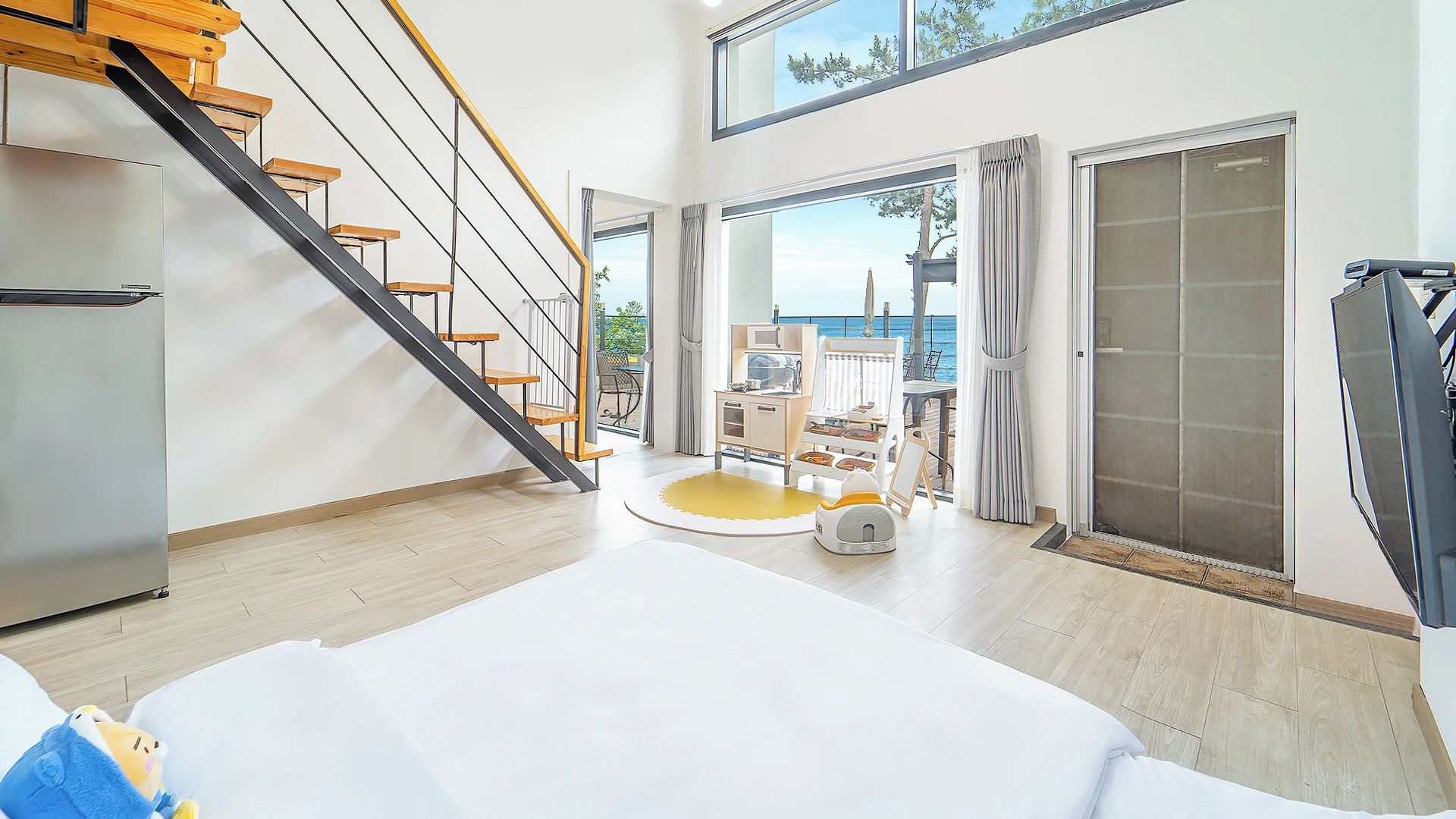 A modern interior with a staircase, a dining area, and a view of the sea.
