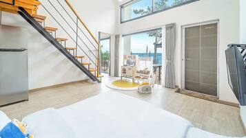 A modern interior with a staircase, a dining area, and a view of the sea.