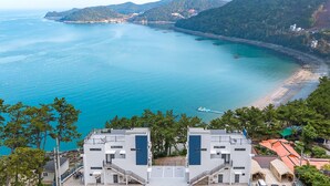 A coastal view with a clear sky, a beach, and a mountainous backdrop. - Yeosu Sea&blue Family Pension (Yeosu)