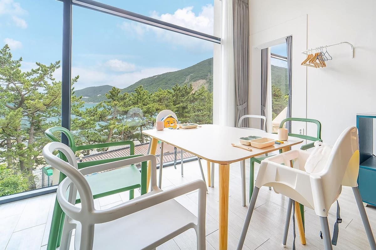 A balcony with a table and chairs, a view of a mountainous landscape, and a kitchenette with a coffee maker.