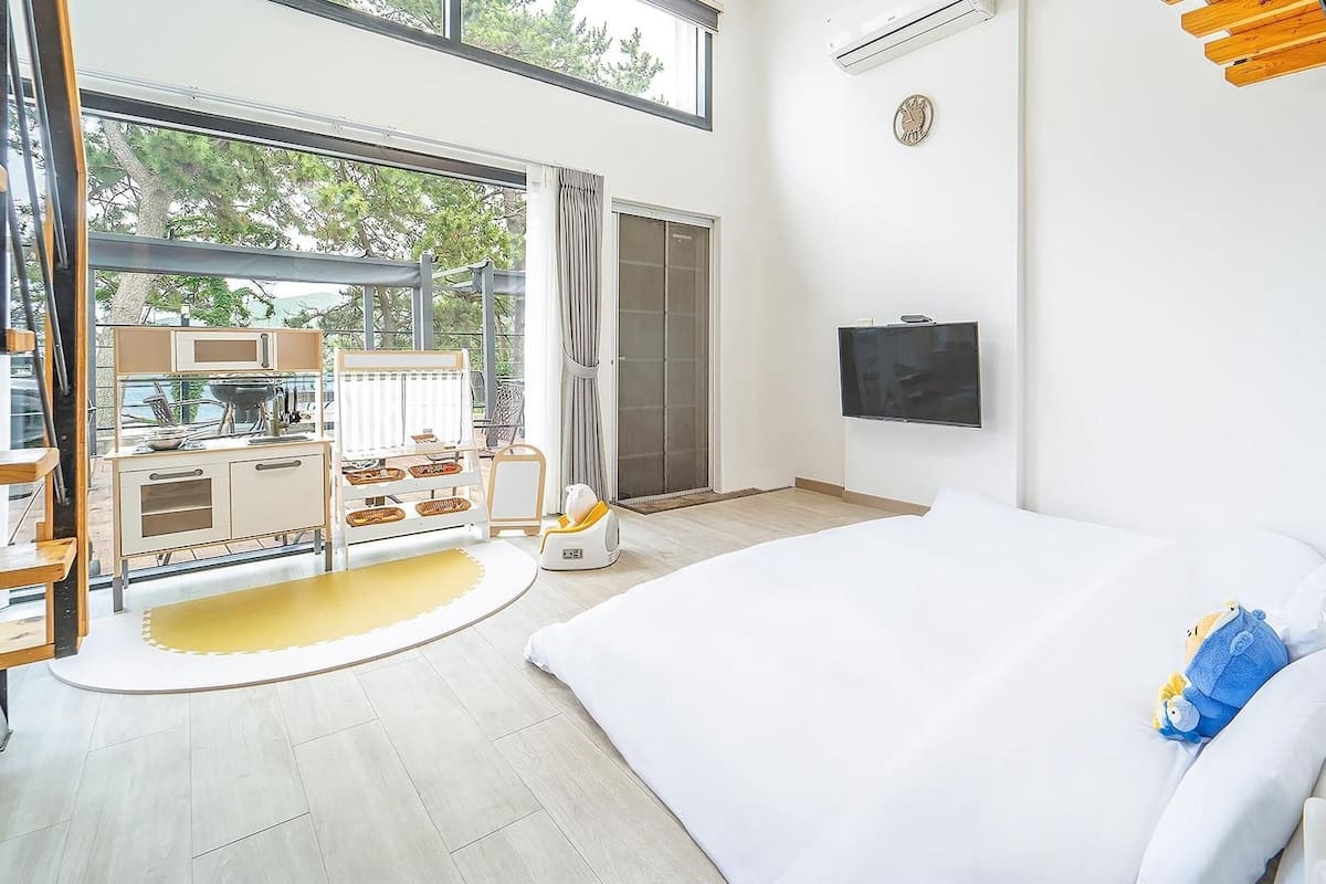 A modern bedroom with a large bed, a TV, and a balcony with outdoor furniture.