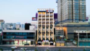 A multi-story hotel with a modern design, featuring balconies on each floor, a visible entrance with a ramp, and signage in a foreign language. - Chungjangro 1st Boutique Hotel (Gwangju)