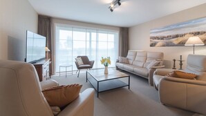 Un salon moderne comprenant un canapé, des fauteuils, une table basse et un téléviseur.