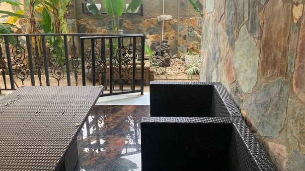 Un espace patio aménagé avec des meubles en osier, un mur en pierre et un petit jardin de rocaille.