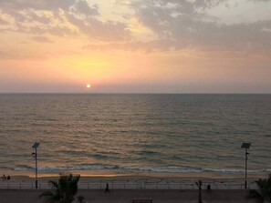 A sunset over a beach with calm waters, a few people walking, and solar-powered lights along the walkway. - Big Seafront Apartment in Saida, Lebanon (Saida)