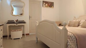 Una camera da letto con un letto, una cassettiera, una toeletta con uno specchio e una porta.