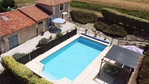 A rectangular swimming pool with a tiled deck, surrounded by a low stone wall and a hedge. - Chez Goret Gites - Gite Skippy  Couples only (Nouvelle- Aquitaine)