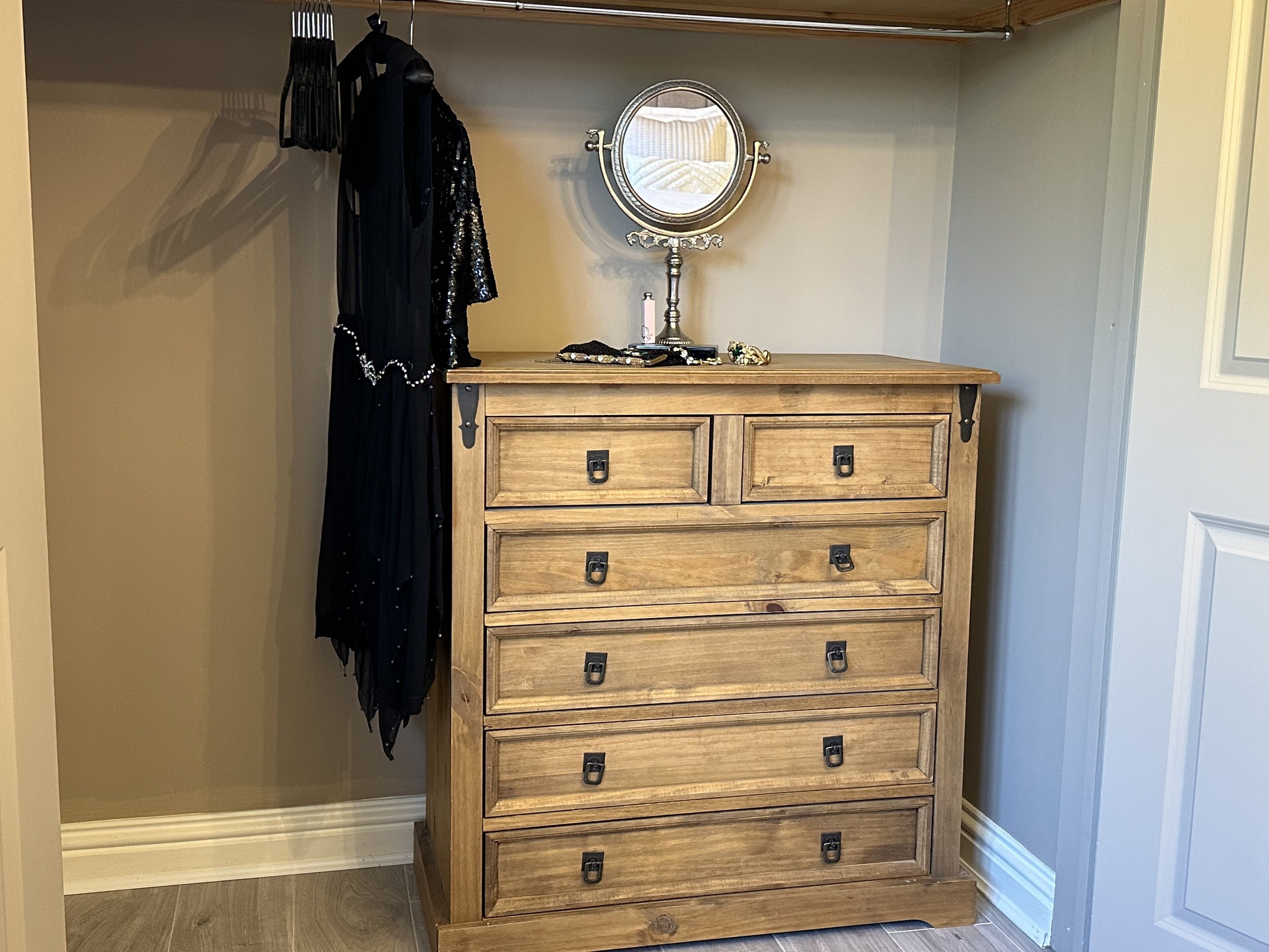 A wooden dresser with multiple drawers and a round mirror on top.