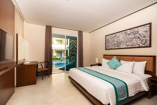 Habitación de hotel con cama, escritorio, silla, televisor y vista a una piscina al aire libre.