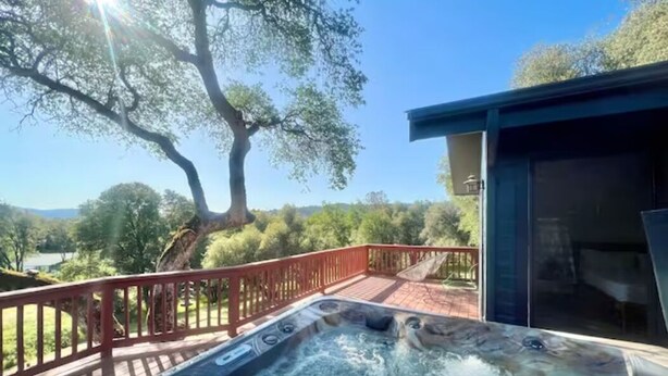 Una vasca idromassaggio su un patio con vista su alberi e cielo sereno.