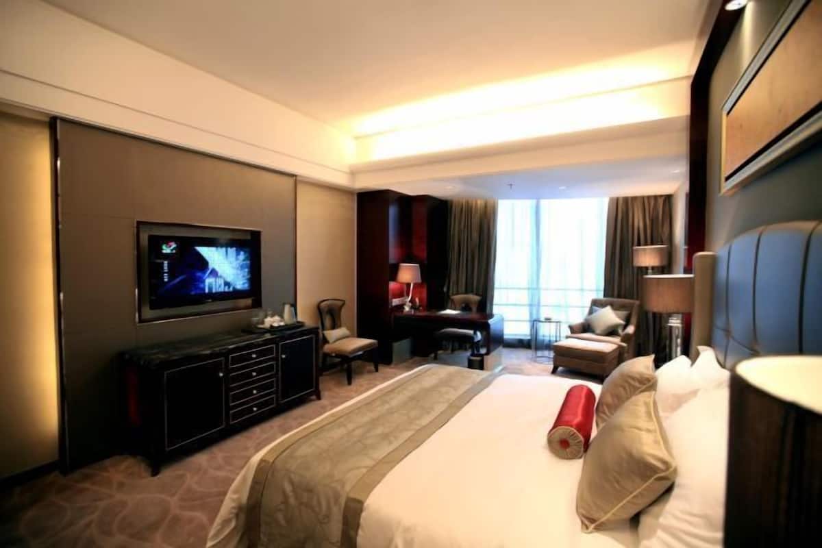 Une chambre d’hôtel avec un grand lit, une télévision, un bureau et une chaise.