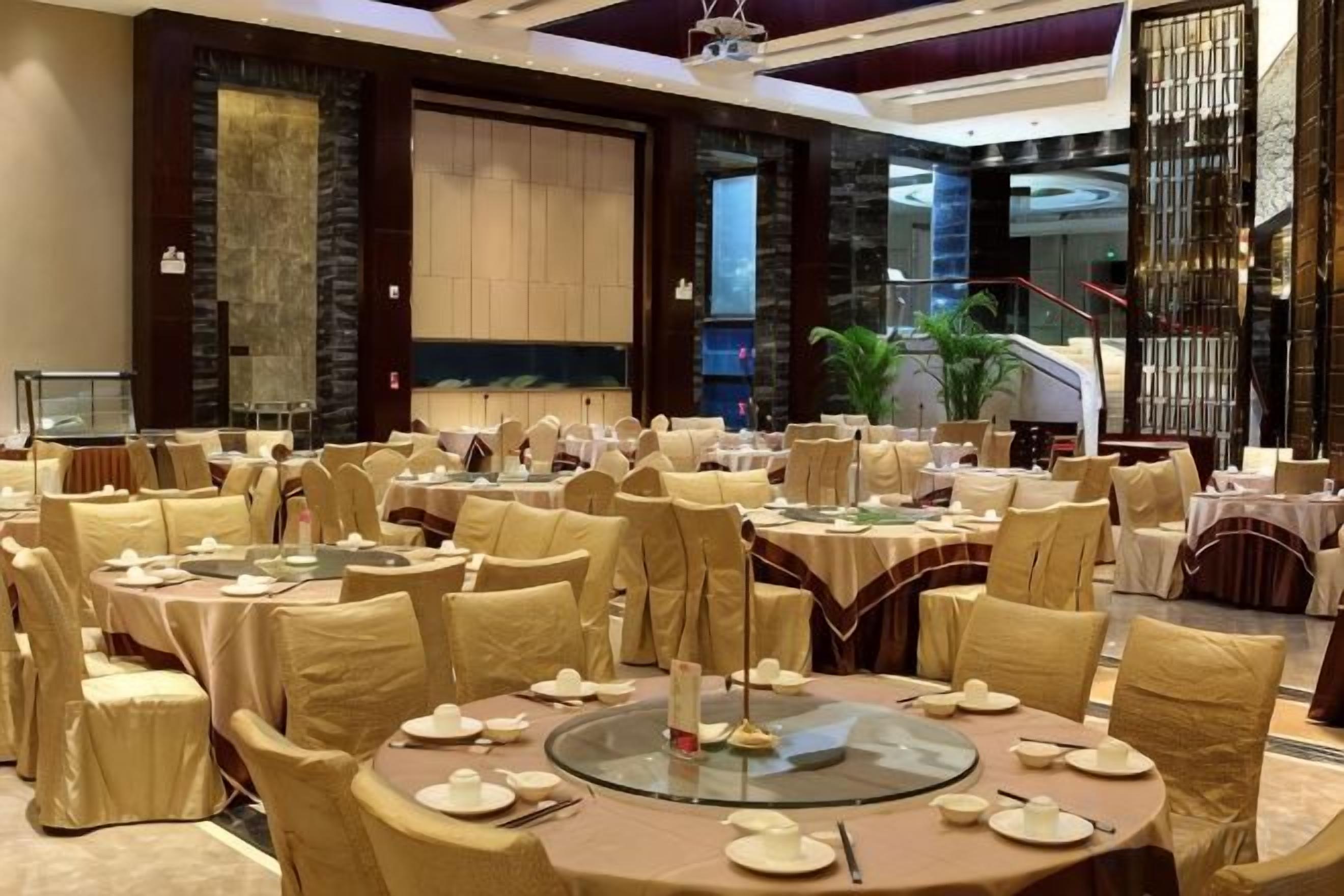 A banquet hall with round tables, chairs, and a central decorative element.