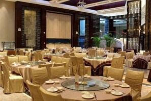Une salle de banquet avec des tables rondes, des chaises et un élément décoratif central.