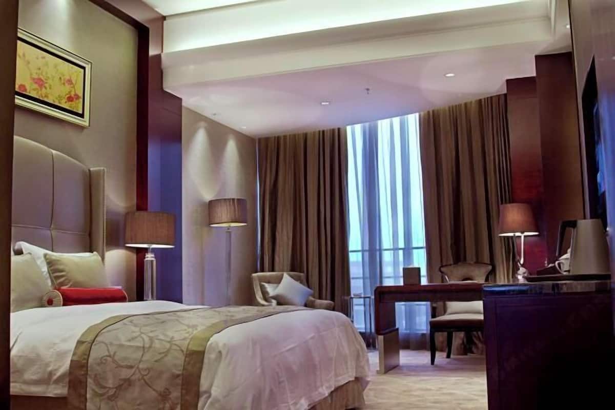 Une chambre d’hôtel avec un grand lit, un bureau, une chaise et un téléviseur.