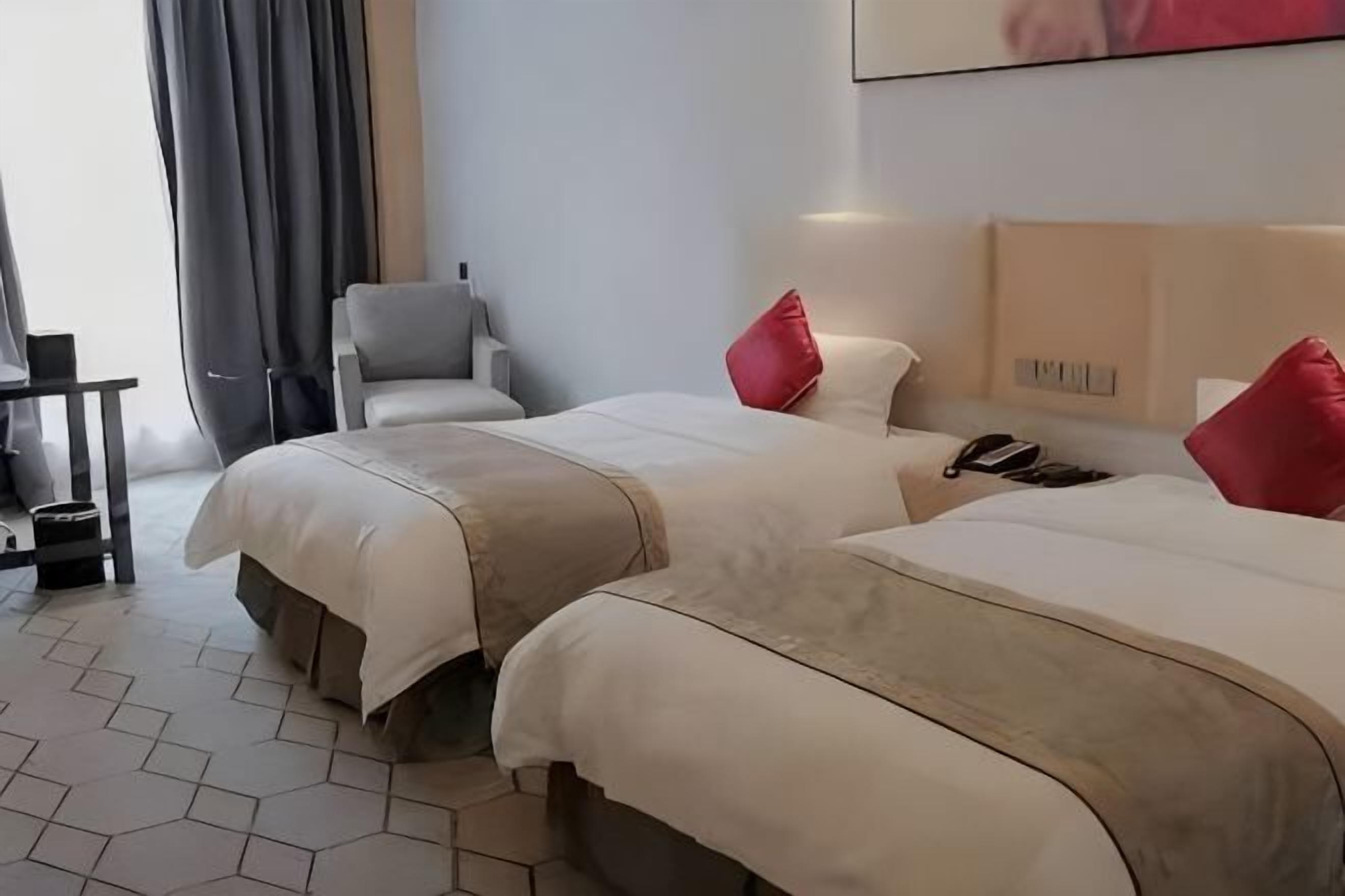 A hotel room with two beds, a chair, a desk, and a phone on the nightstand.
