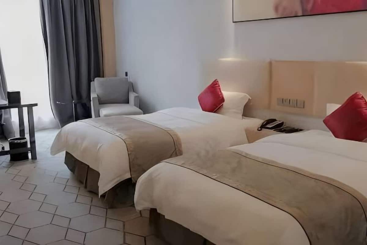 Une chambre d’hôtel avec deux lits, une chaise, un bureau et un téléphone sur la table de chevet.