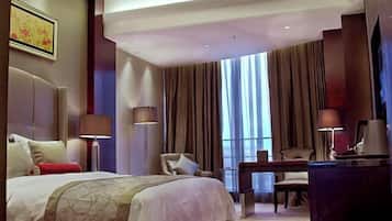 Quarto de hotel com uma cama grande, uma escrivaninha, uma cadeira e uma televisão.