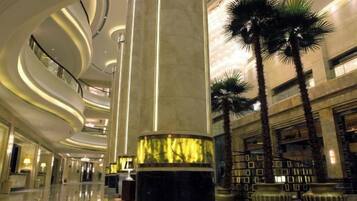 A spacious lobby with a central column, palm trees, and a curved ceiling design.