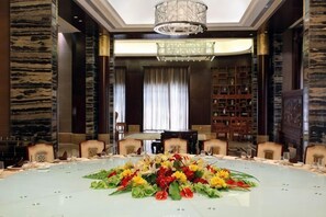 A conference room with a round table, chairs, a chandelier, and bookshelves.