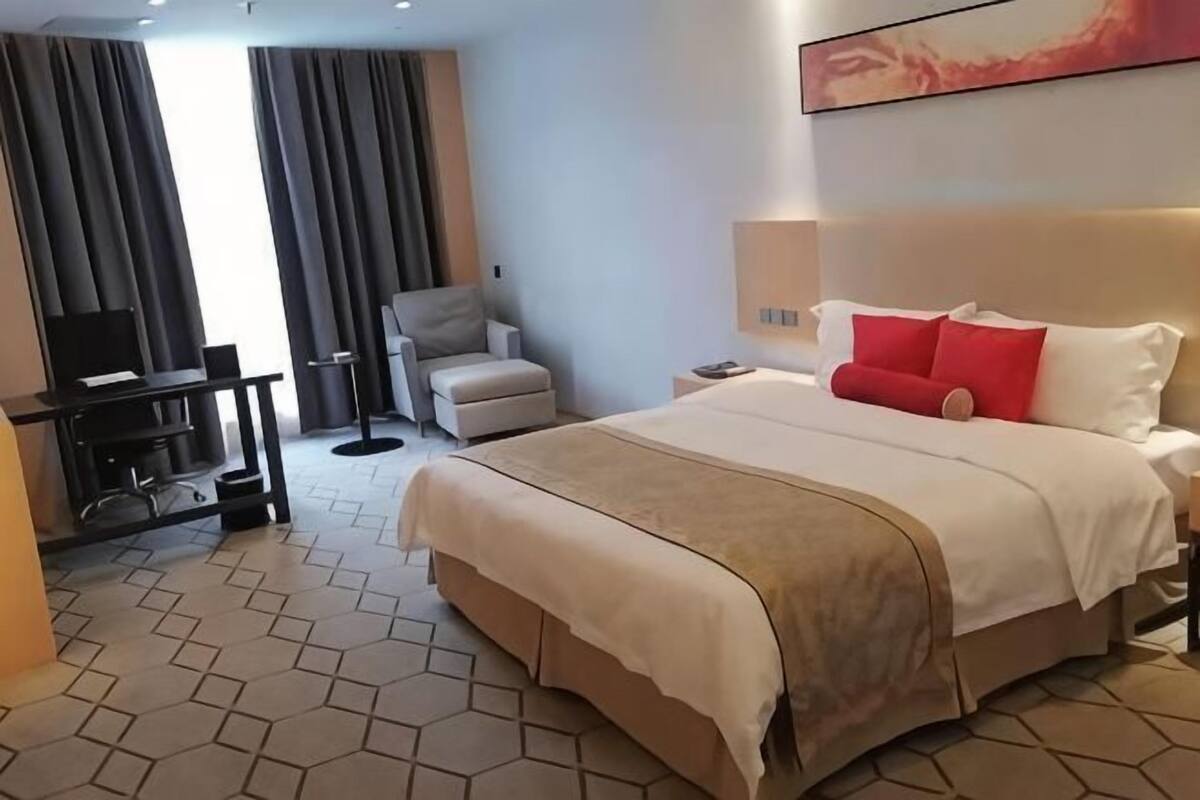 Une chambre d’hôtel avec un grand lit, un bureau, une chaise et un téléviseur.