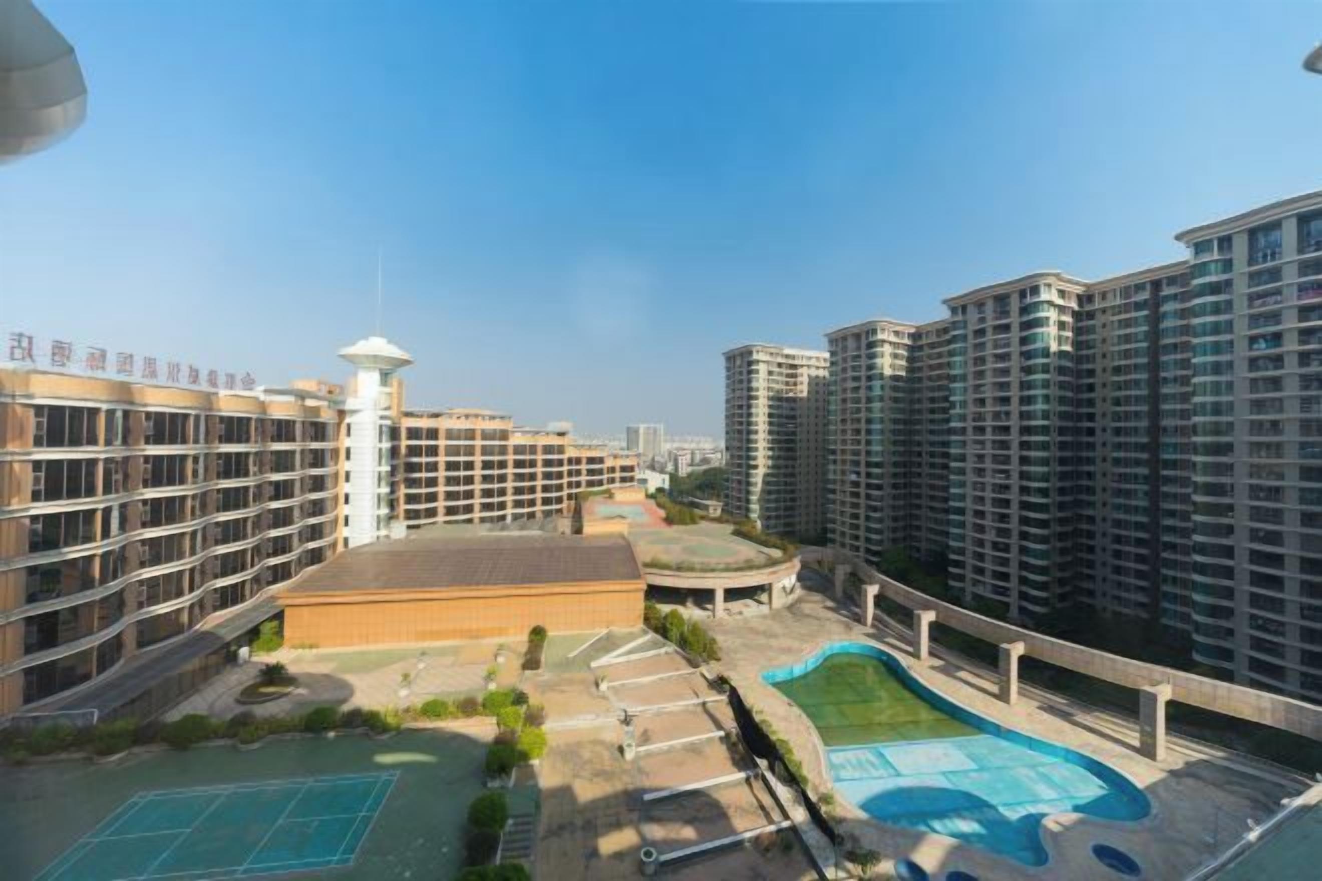 Un conjunto residencial con varios edificios de gran altura, un patio central con cancha de baloncesto y una pequeña torre.