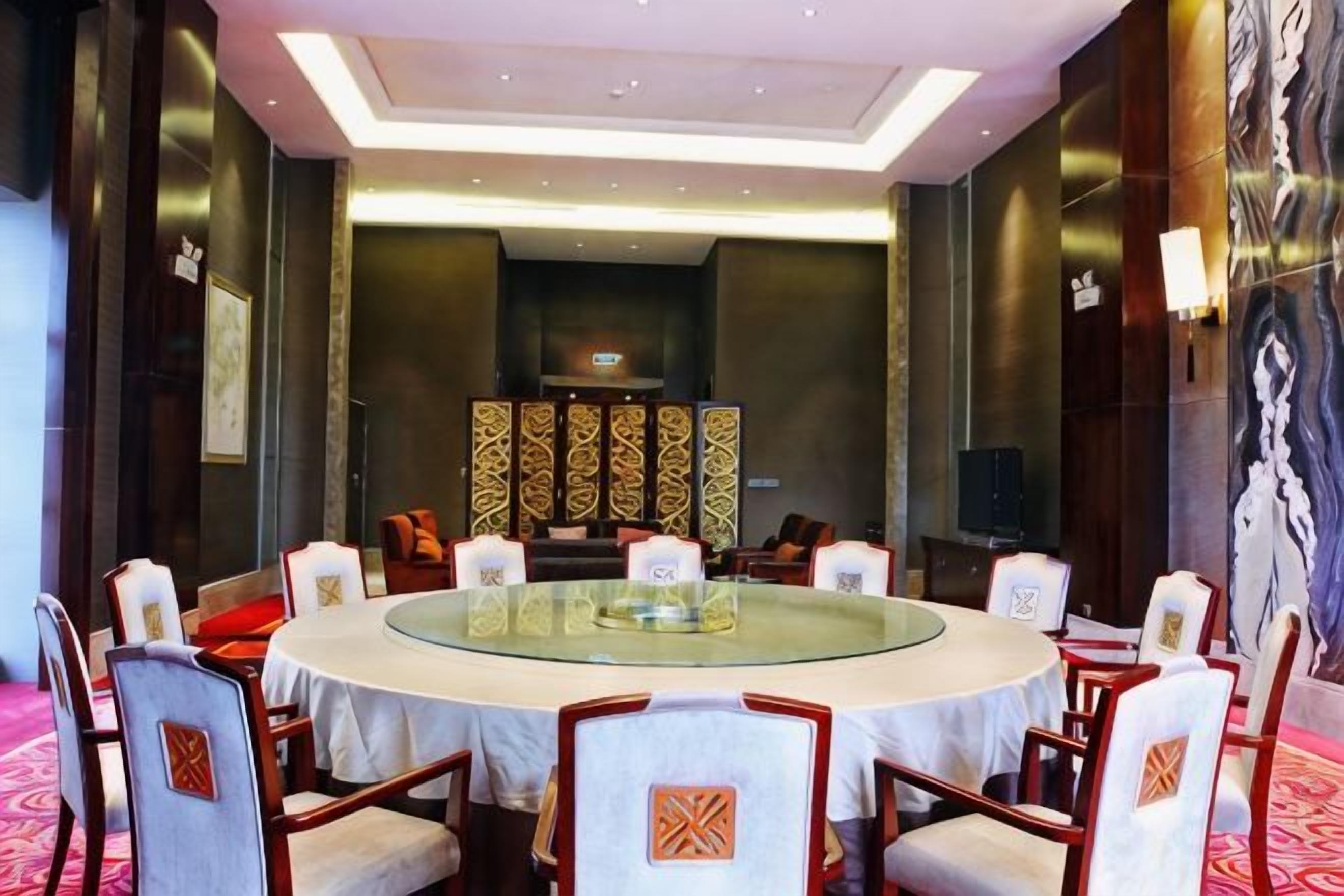 A conference room with a round table, chairs, and a television.