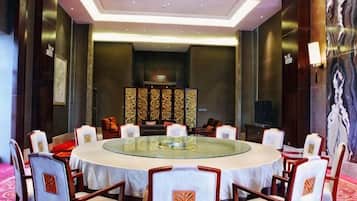 A conference room with a round table, chairs, and a television.