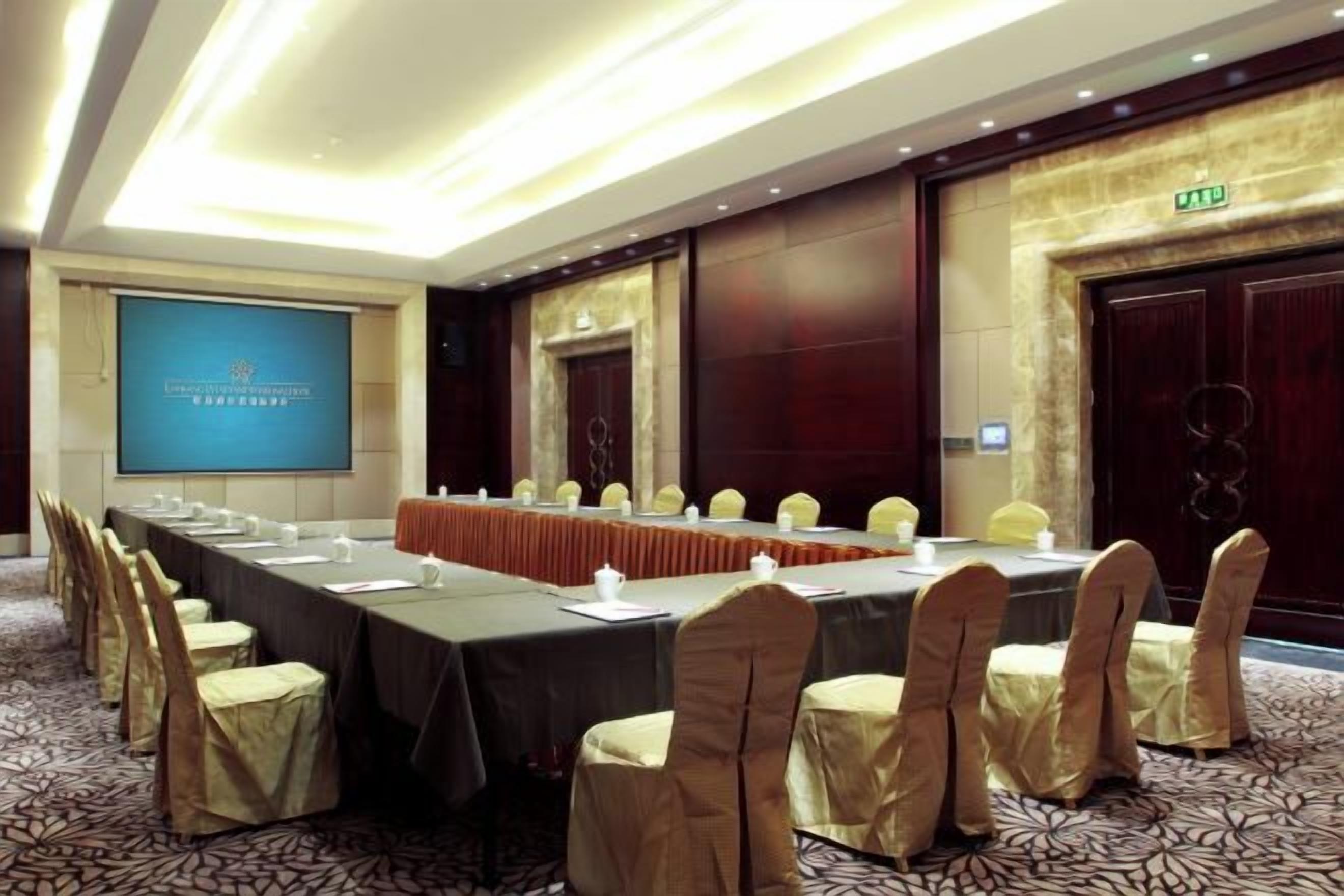 A conference room with a long table, chairs, and a projector screen.