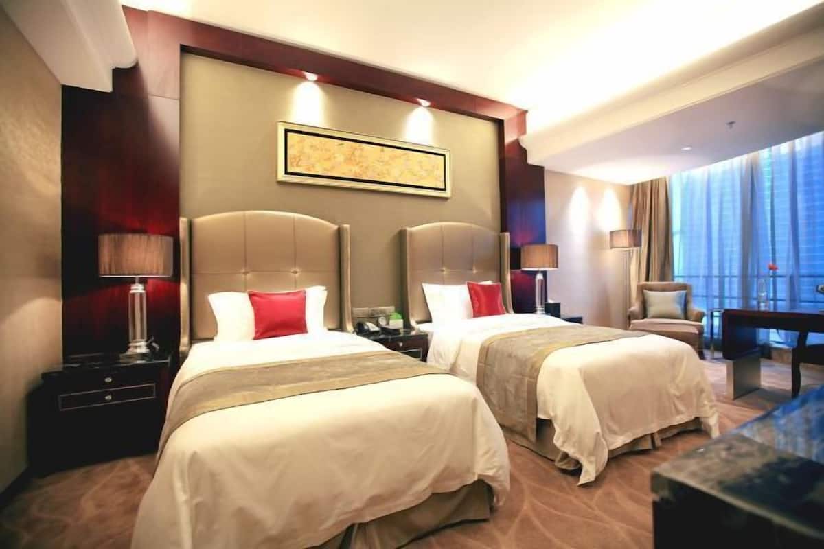 Une chambre d’hôtel avec deux lits, une grande fenêtre, un bureau et une chaise.