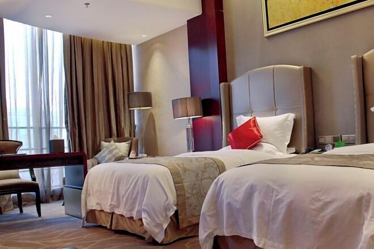 A hotel room with two beds, a desk, and a chair.
