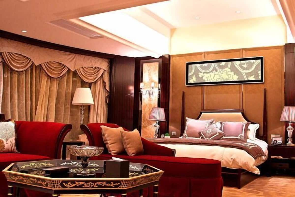 Une chambre d’hôtel avec un grand lit, un canapé rouge, une petite table et un miroir.