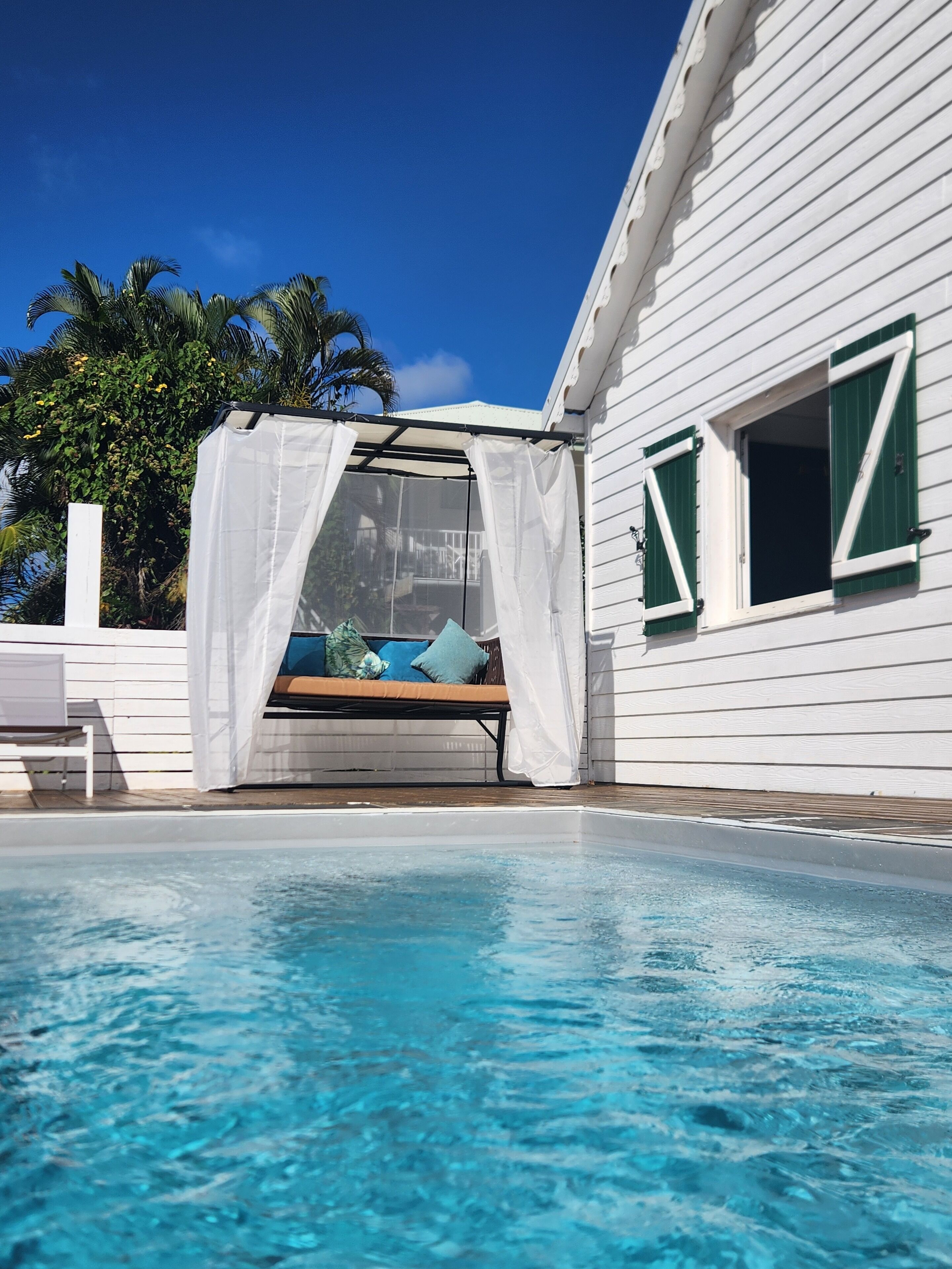 A poolside area with a covered seating area and a view of the pool.
