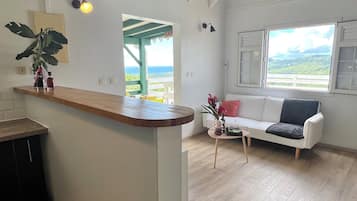 A spacious living area with a wooden bar, a white sofa, and a view of the outdoors.