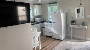 Une cuisine de taille réduite avec des meubles blancs, un four à micro-ondes, un réfrigérateur, une cuisinière et un ventilateur de plafond.