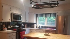 A modern kitchen with white cabinets, a stainless steel refrigerator, a microwave, and a stove. - Beautiful Private Cottage, Sleeps 6, Walk to Beach (New Buffalo)