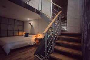 A bedroom with a bed, bedside table, lamp, and a staircase with wooden steps and metal railings. - Punk Ballet Ins Hotel (Changzhou Dinosaur Park) (Changzhou)