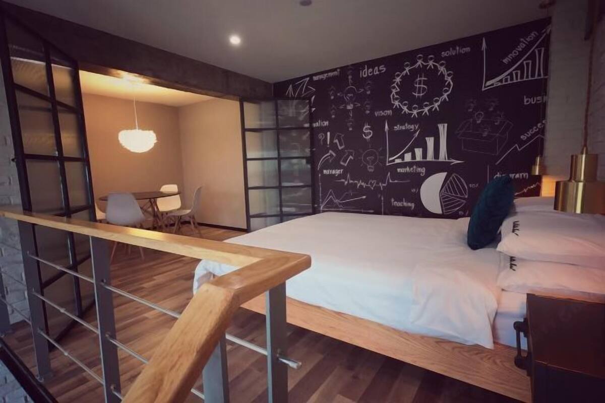 A modern bedroom with a large bed, a desk, and a chair.