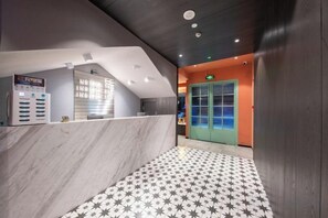 A reception area with a marble counter, a patterned floor, and a green door. - Punk Ballet Ins Hotel (Changzhou Dinosaur Park) (Changzhou)