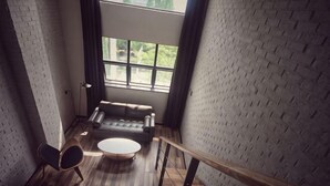 A loft-style room with a brick wall, a sofa, a round coffee table, and a chair. - Punk Ballet Ins Hotel (Changzhou Dinosaur Park) (Changzhou)
