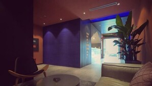 A modern lobby with a dark-colored sofa, a round coffee table, and a potted plant. - Punk Ballet Ins Hotel (Changzhou Dinosaur Park) (Changzhou)