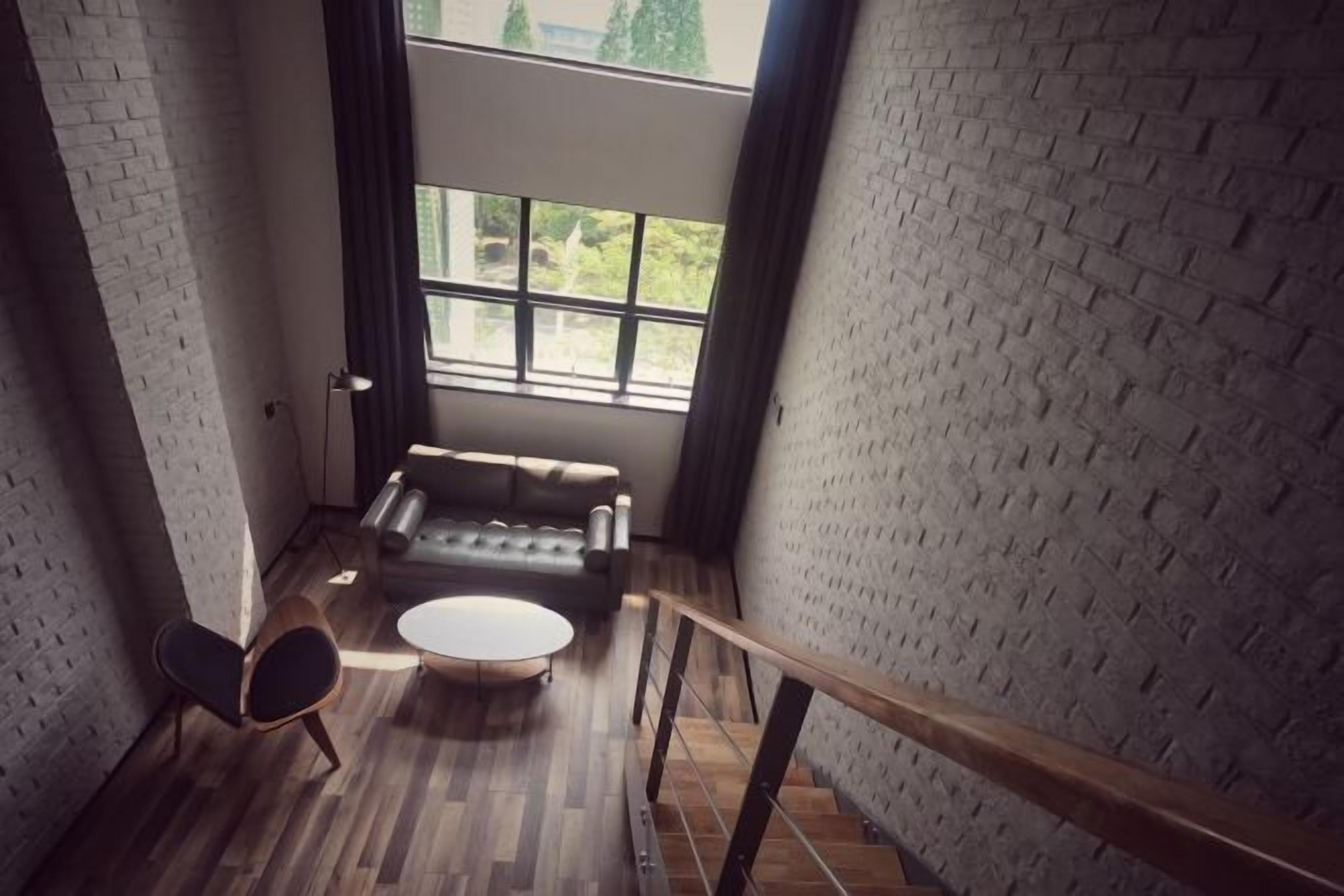 Una habitación con pared de ladrillo, un sofá, una mesa redonda y una silla.