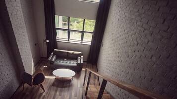 Una habitación con pared de ladrillo, un sofá, una mesa redonda y una silla.