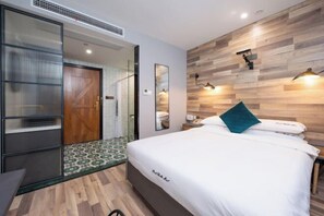 A modern hotel room with a bed, a nightstand, a mirror, and a wooden wall panel. - Punk Ballet Ins Hotel (Changzhou Dinosaur Park) (Changzhou)