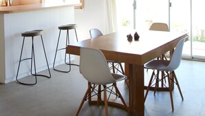 A modern kitchen with wooden beams, a large island, bar stools, and pendant lighting. - Peaceful mid-century house under the boulders near Joshua Tree National Park (Joshua Tree)